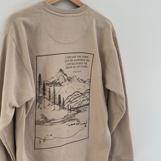 Back of the light tan sweatshirt depicting Psalm 34:4 text on a mountain scene graphic