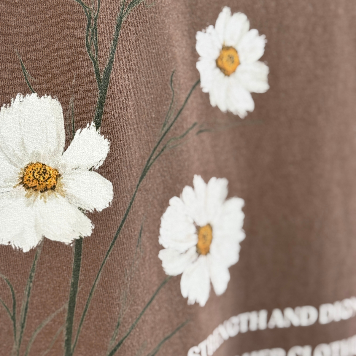 Close up of the White flowers with yellow centers on a brown tshirt. 