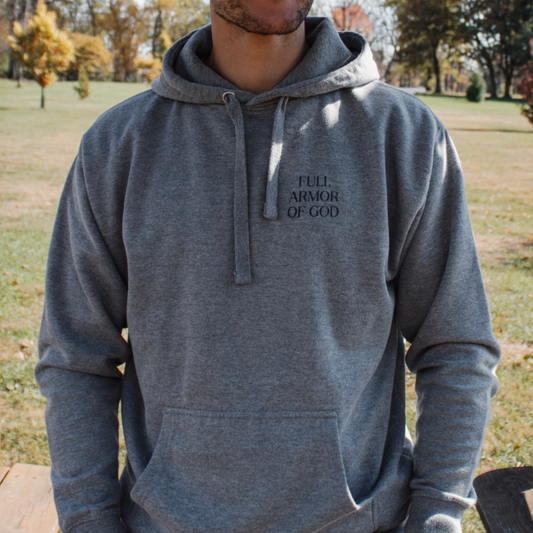 Person wearing a gray hoodie with 'Full Armor of God' text outdoors.