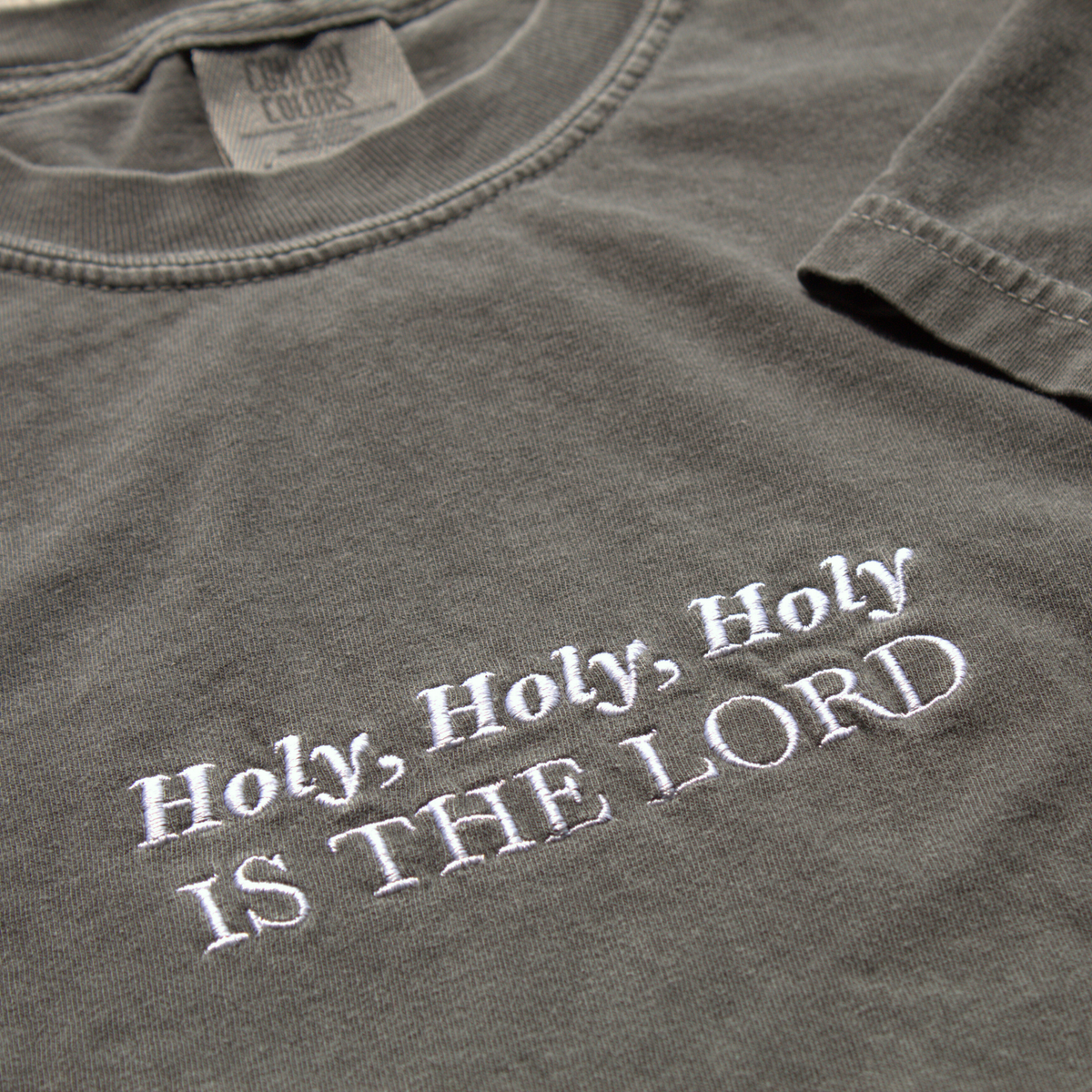 close up of Gray t-shirt with 'Holy, Holy, Holy IS THE LORD' text in white embroidery.