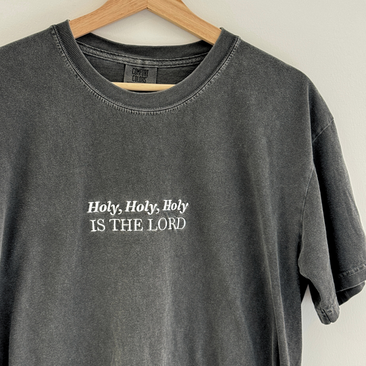 Gray t-shirt with embroidered 'Holy, Holy, Holy IS THE LORD' text on a wooden hanger.