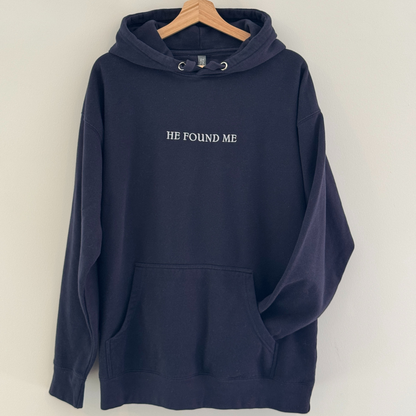 Navy blue hoodie with embroidered 'HE FOUND ME' text on a white background