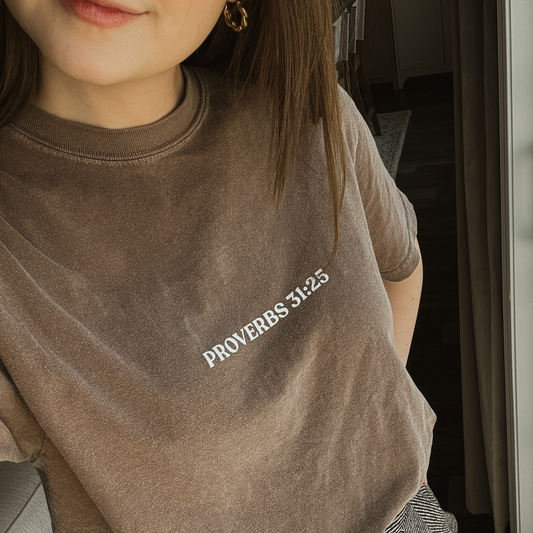 Person wearing a brown t-shirt with 'Proverbs 31:25' text on the front middle. 
