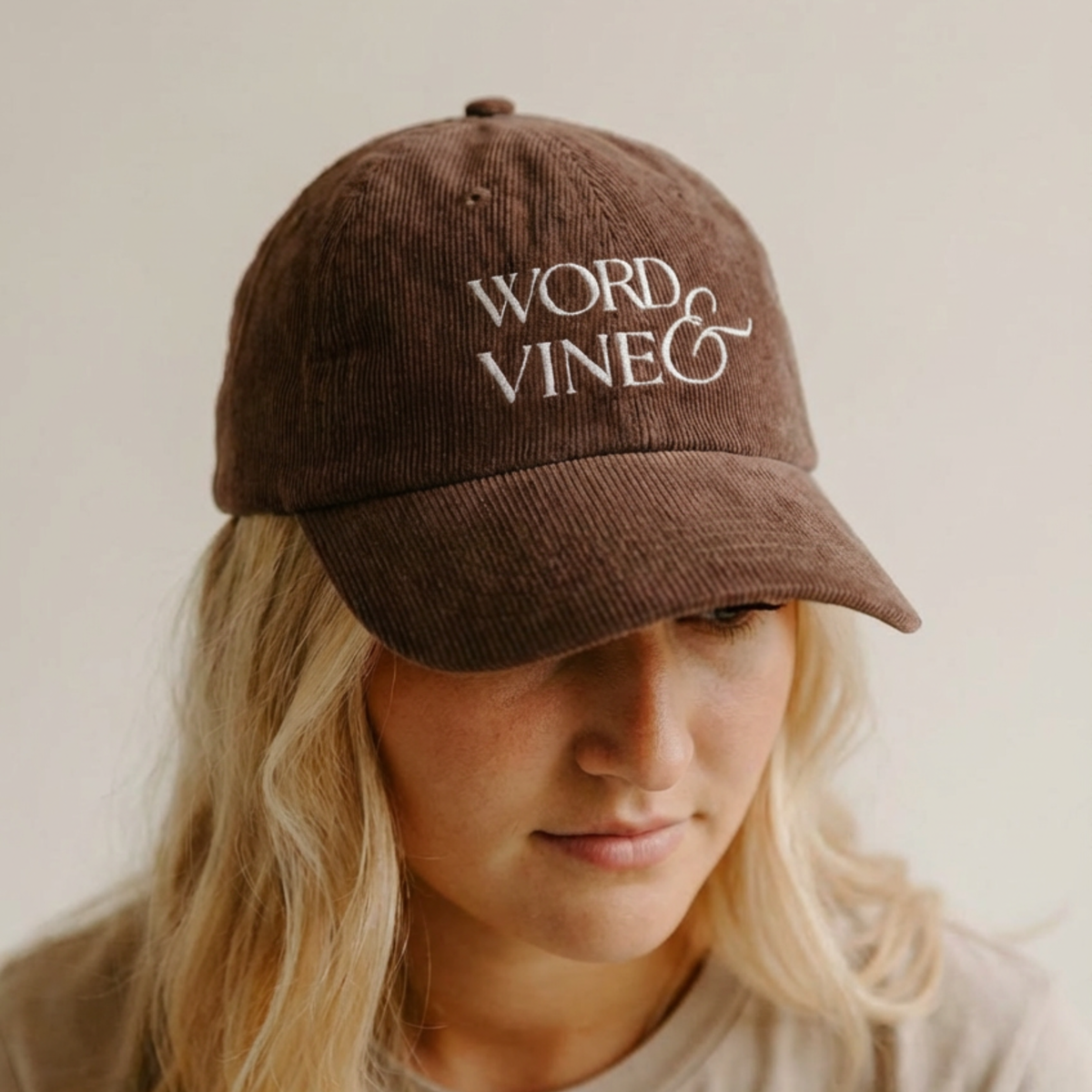 the Brown Corduroy ball cap with embroidered 'WORD & VINE' logo worn by a person against a neutral background taken at an angle. 