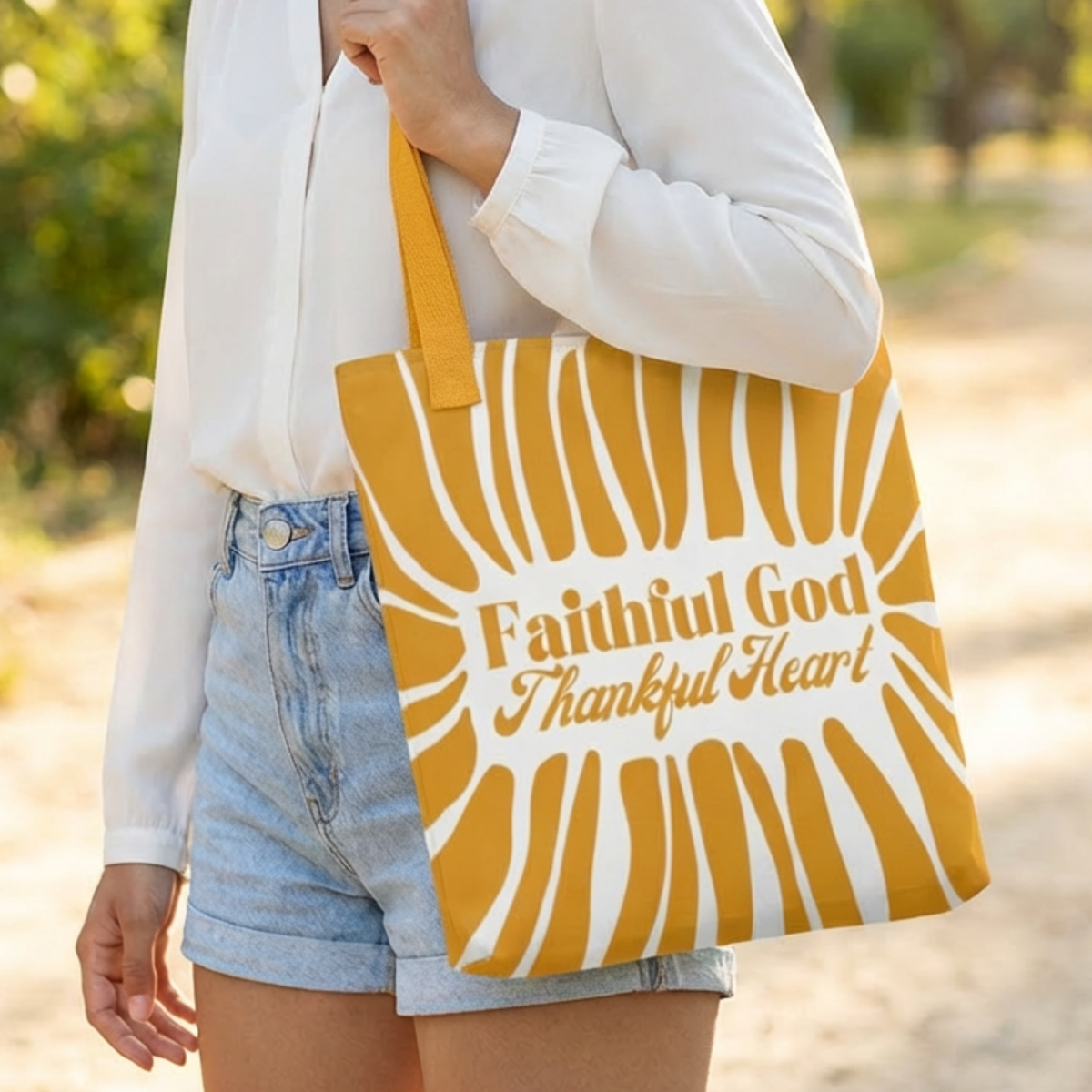 Person holding a tote bag with 'Faithful God, Thankful Heart' text outdoors.