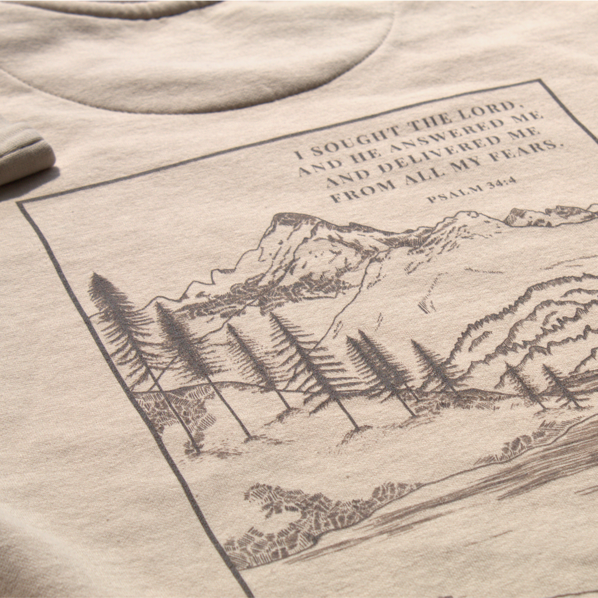 light tan sweatshirt close up of the back with mountain scene design and Psalm 34:4 text