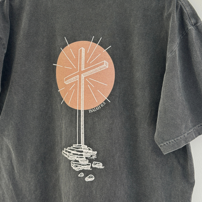 Close up of the Gray t-shirt with a graphic design of an empty cross in front of a peach colored circle on the back.
